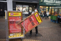 © Licensed to London News Pictures. 19/12/2020.
Dartford, UK. A Dartford council worker putting out very high threat level covid posters in the high street. Christmas shoppers in Dartford, Kent this morning on the last shopping weekend before Christmas. People wearing masks and social distancing to protect themselves against the threat of the new Coronavirus mutant strain which could see more restrictions imposed in the county. Photo credit:Grant Falvey/LNP