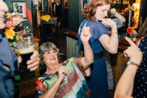 Wedding guests dance at the bar in an English pub