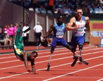 L-R Ntando Mahlangu (RSA) takes a fall, whilst Regas Woods SR (USA) Richard Whitehead of Great Britain finish race compete in Men's 100m T42 Round 1 Heat 1during IPC World Para Athletics Championships at London Stadium in London on July 17, 2017