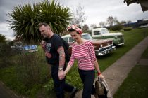 © London News Pictures. 11/05/2013. Hemsby, UK. A couple walk hand in hand dresses in 1950's outfits past classic American cars as  Rock and Roll enthusiasts gather at the Hemsby Rock 'n' Roll Weekender  in Hemsby, Norfolk. Twice a year rock and roll enthusiasts gather in the grounds of the Authentic 1950s Seacroft Holiday Site to re-live the 50's by dressing in keeping with the period and listening to live bands playing jive, hop, bop and Rock 'n' Roll. Photo credit: Ben Cawthra/LNP