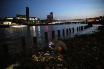 A mudlarker uses a torch to look for items on the bank of the river Thames in London, Britain June 06, 2016. When the river Thames is at low tide, mudlarkers scour the shore for historical artefacts and remains from there City of London's ancient past. Finds can date back to Roman times to when the city was found up until more recent times. Anyone can walk along the river and look for finds, but the uses of metal detectors and digging is restricted. Mudlarkers need to be licences by the Port of London Authority. All find should be register with the Museum of London. REUTERS/Neil Hall