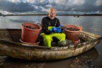 Oyster Farmer Bill Pinney sits on the banks of the the river Alde at his Oyster farm in Orford Suffolk. Oyster yields are up this year following a cool summer.