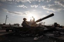 A member of the Free Syrian Army sends a message from his phone while sitting on top of a destroyed tank   in the town of Azaz, Syria, on Monday 10th of September [Sam Tarling]