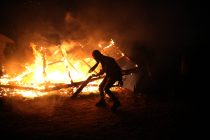 A migrant burns his temporary shelter as the '"The Jungle" migrant camp is cleared in Calais, France October 25, 2016. REUTERS/Neil Hall