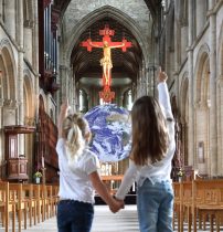 Two little girls point to the 'Gaia' Earth in Peterborough Cathedral. Peterborough Cathedral is hosting a touring artwork 'Gaia', of the planet Earth. 'Gaia' has been created by UK artist Luke Jerram, and The Earth, measuring 7 metres in diameter, will be inside Peterborough Cathedral , built in the 12th Century until September 15, 2019. Gaia, Earth artwork, Peterborough Cathedral, Peterborough, Cambridgeshire, on August 19, 2019.